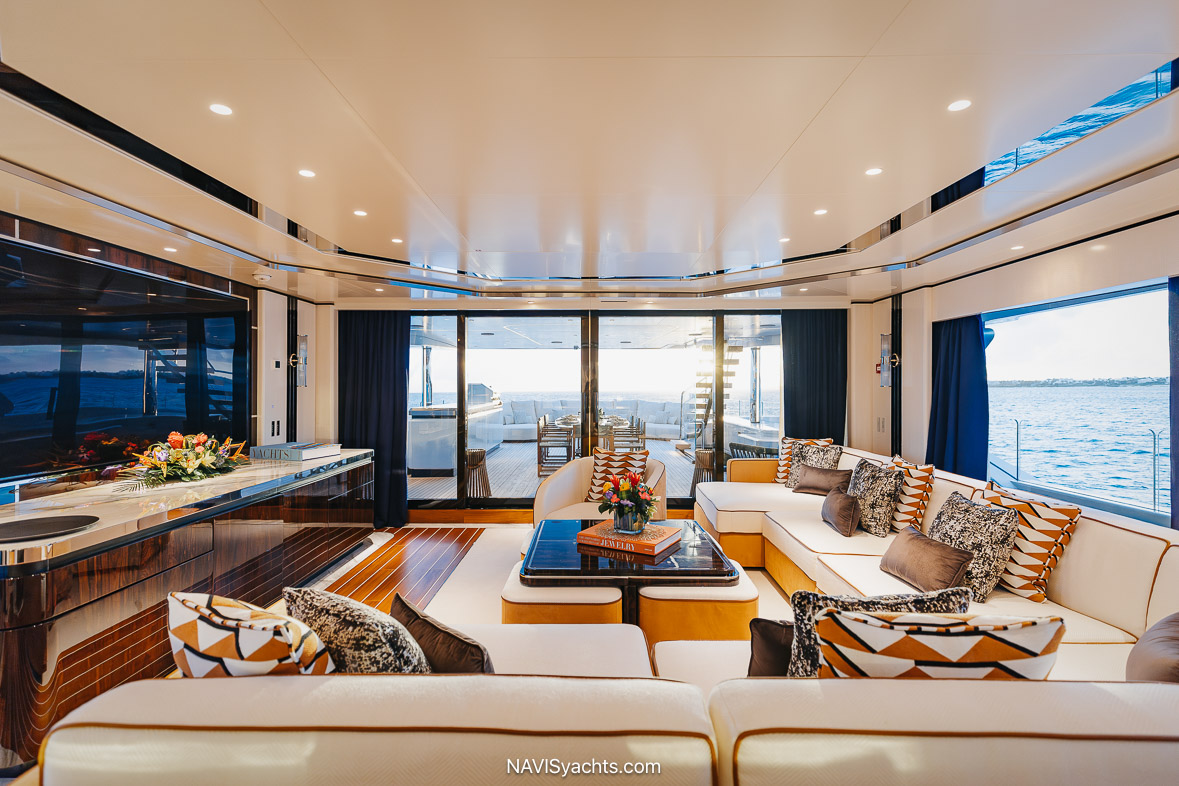 The luxurious main salon of the motor yacht Daybreak, showcasing the art deco-inspired interior with backlit onyx panels, reeded glass, and expansive windows that create an open, airy atmosphere.