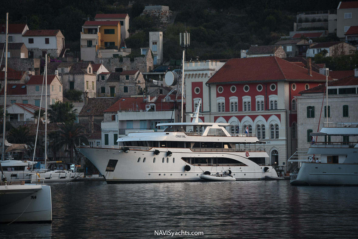 Serene Vis town harbor with yachts moored and historic buildings in the background.