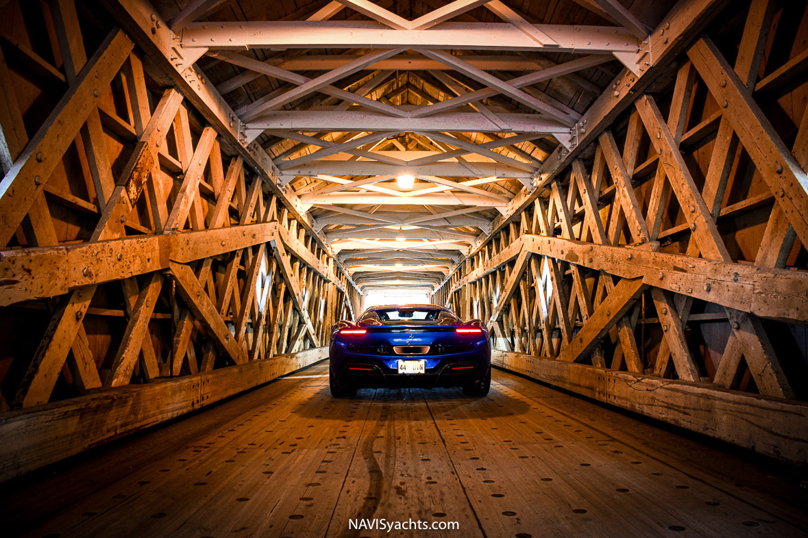 The sleek Ferrari 296 GTS cruising through a covered bridge in Cornwall.