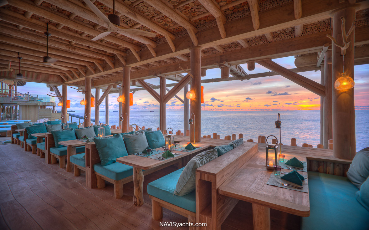 A detail of the dining experience at Out of the Blue, possibly showing artfully plated Asian cuisine, the rustic yet sophisticated table setting with ocean-blue accents, or the unique overwater nets for lounging.